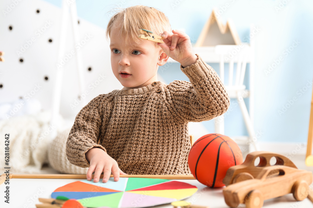 Cute little boy playing matching game with clothespins at home