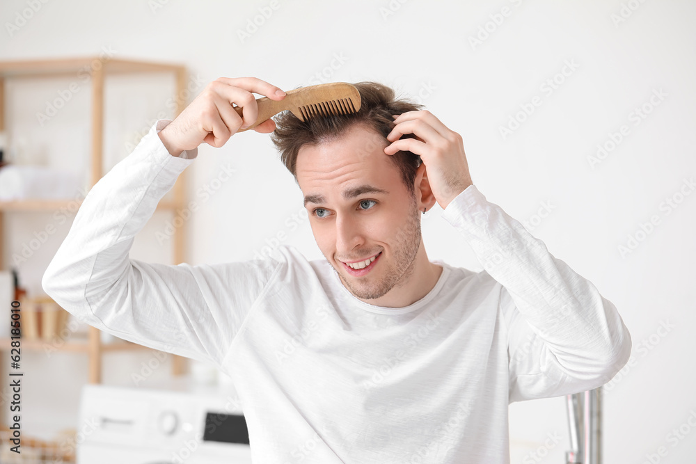 Young man combing hair in bathroom