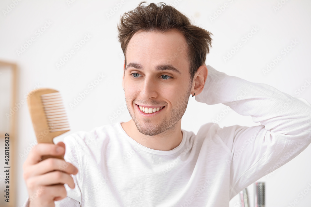 Young man with hair comb in bathroom, closeup