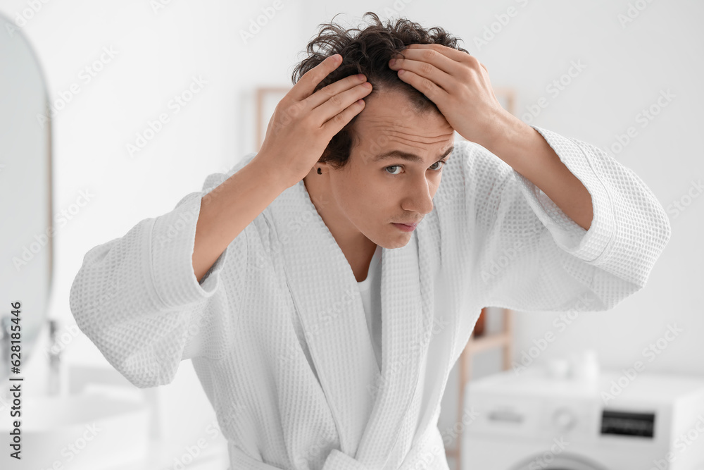 Young man with hair loss problem in bathroom