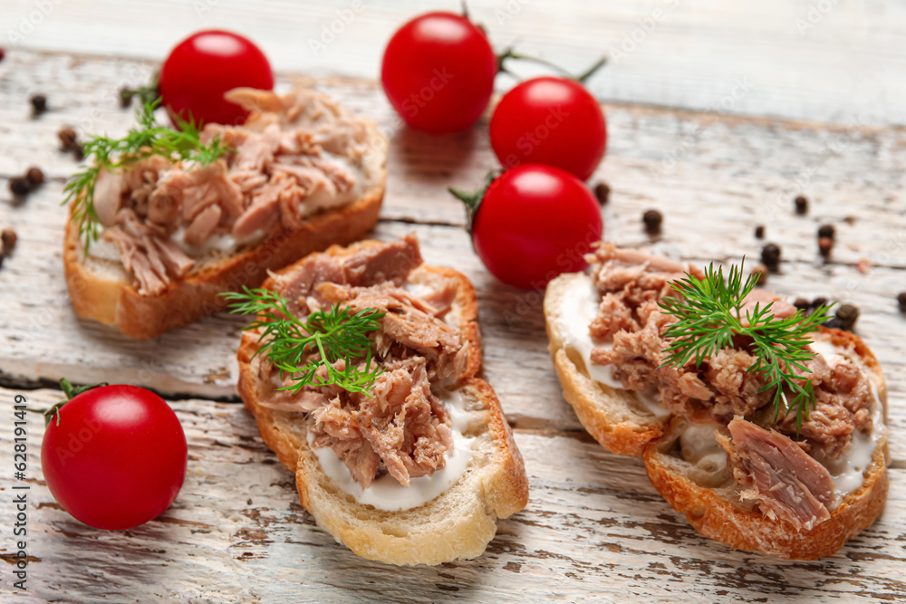 Delicious tuna bruschettas with tomatoes and peppercorn on white wooden table