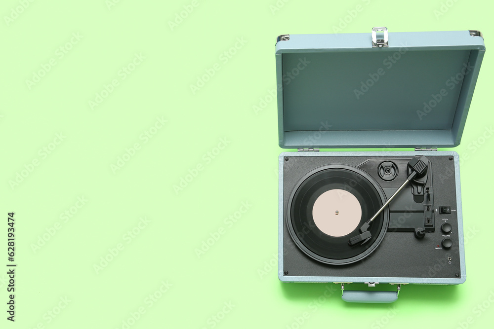 Record player with vinyl disk on green background