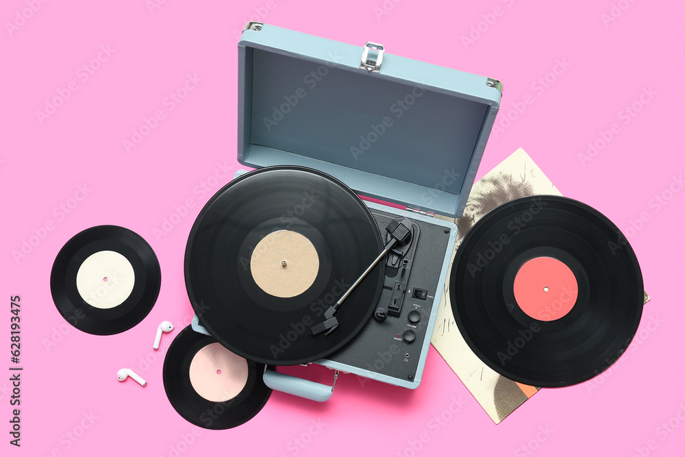 Record player with vinyl disks on pink background