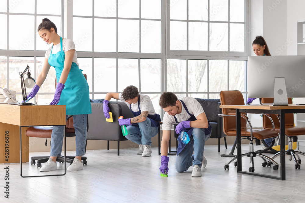 Young janitors cleaning in office