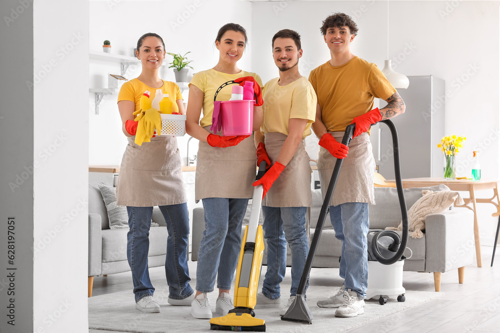 Young janitors with cleaning supplies in kitchen