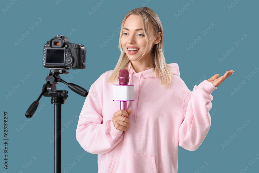 Female journalist with microphone recording video on blue background