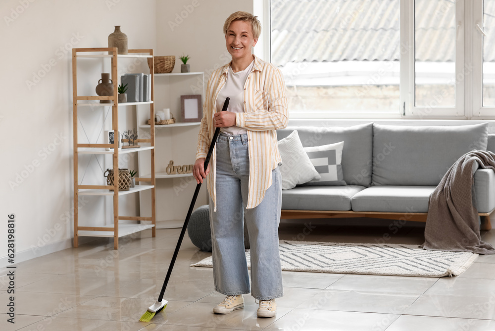 Mature woman sweeping floor in room