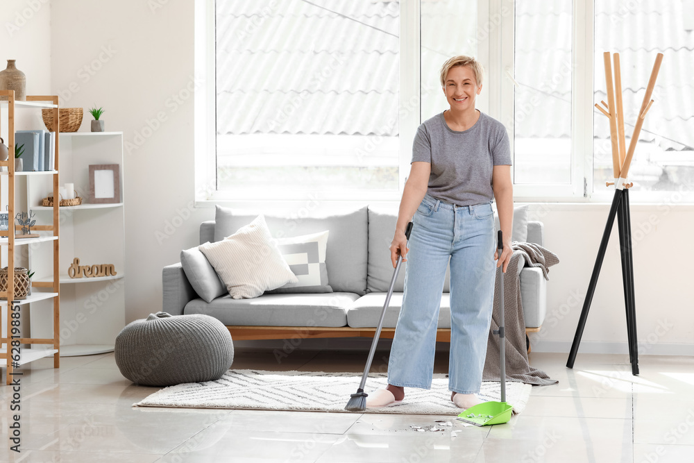 Mature woman sweeping floor in room