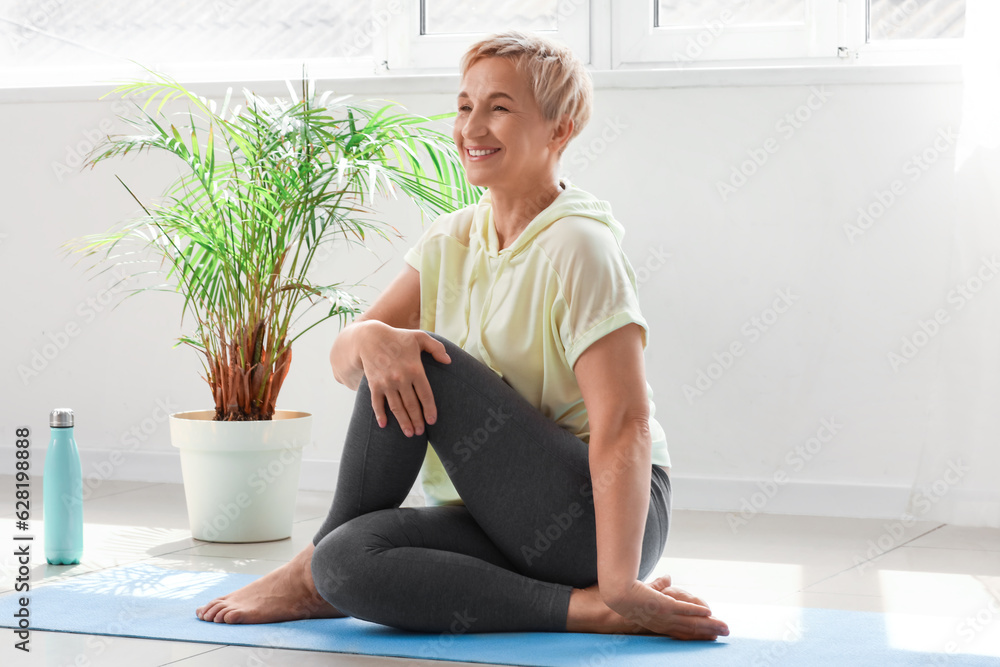 Sporty mature woman practicing yoga at  home