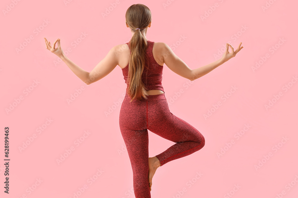 Sporty young woman doing yoga  on pink background, back view