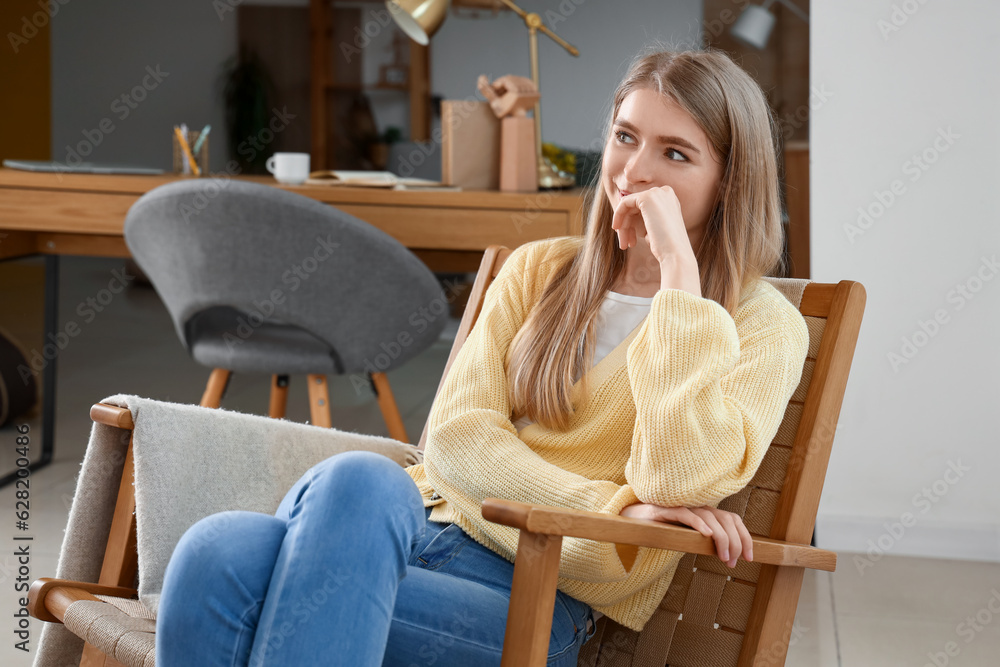 Dreaming young woman in armchair at home