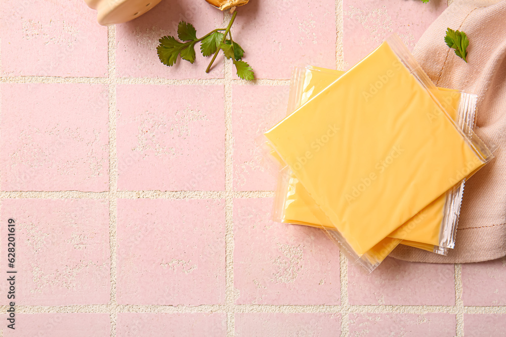 Slices of tasty processed cheese with herbs on pink tile background