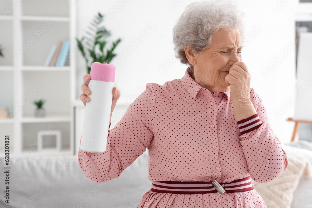 Displeased senior woman with air freshener at home