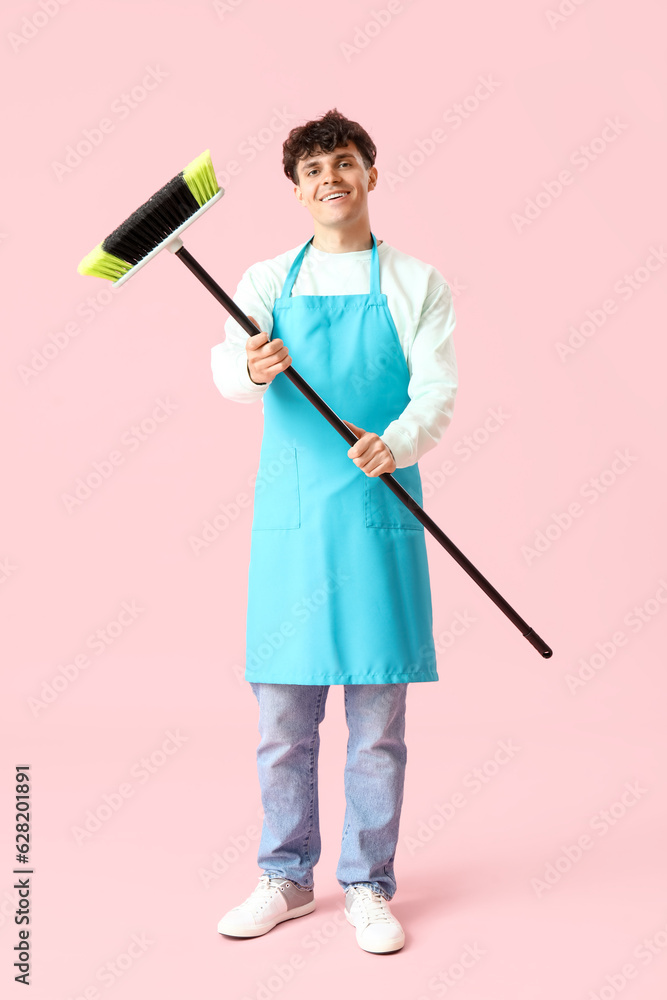 Male janitor with broom on pink background