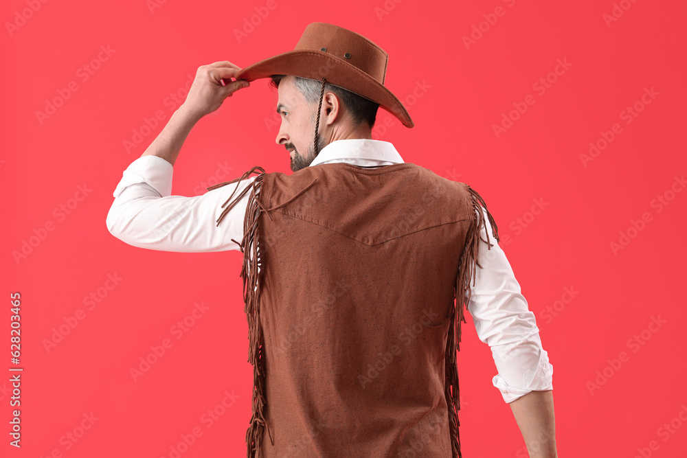 Handsome cowboy on red background, back view