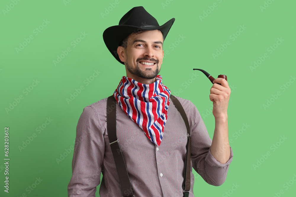 Handsome cowboy with smoking pipe on green background