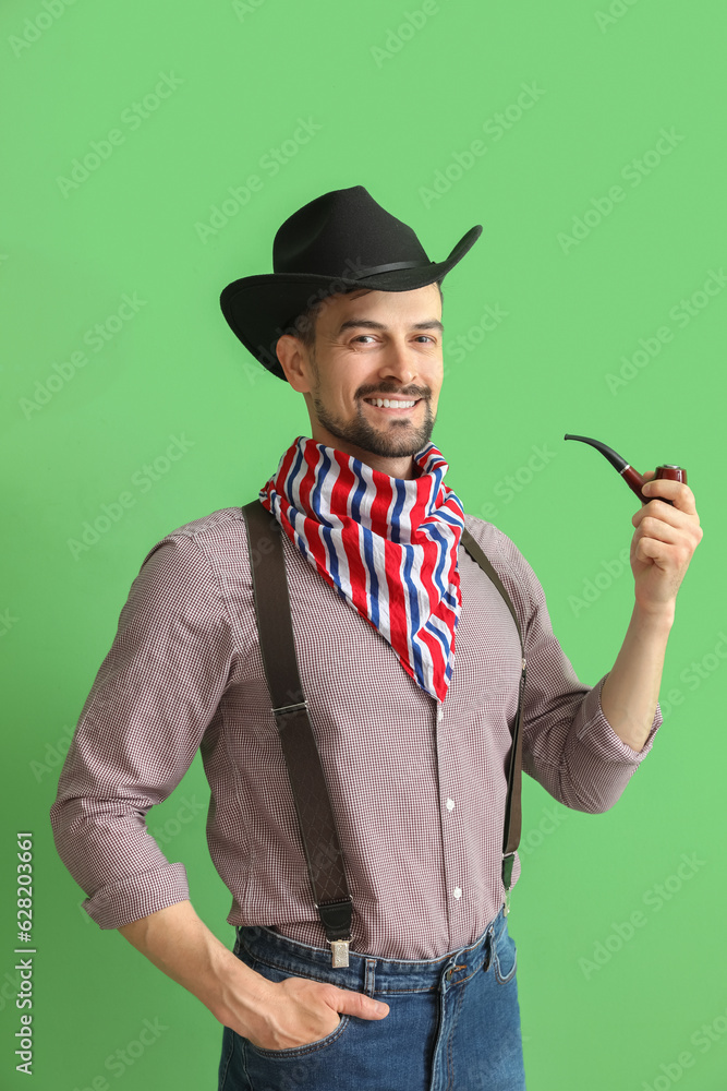 Handsome cowboy with smoking pipe on green background