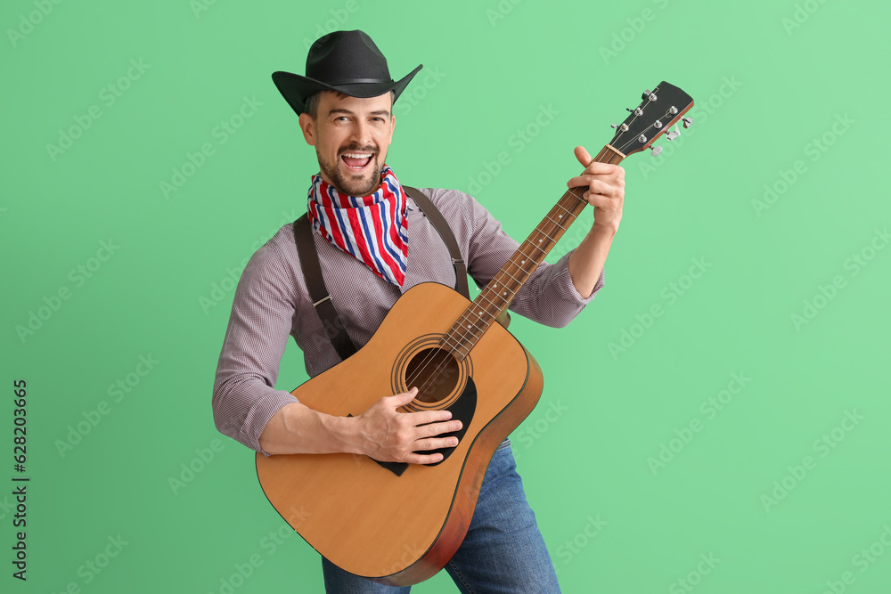 Handsome cowboy playing guitar on green background