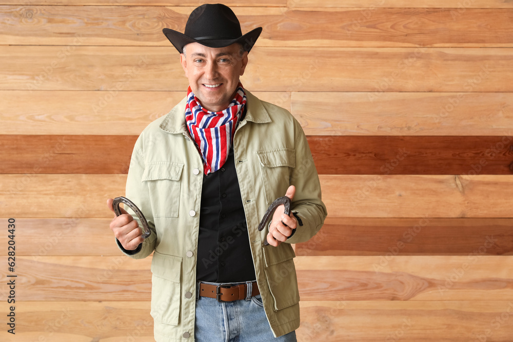 Mature cowboy with horseshoes on wooden background