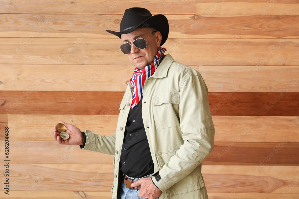 Mature cowboy with compass on wooden background