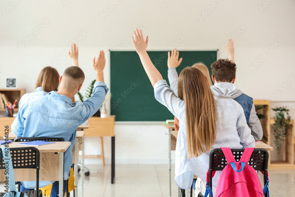 Classmates raising hands to answer in classroom