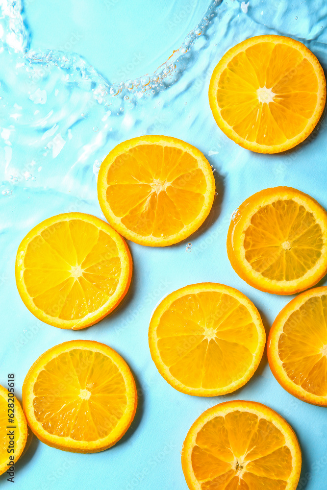 Slices of fresh orange in water on blue background