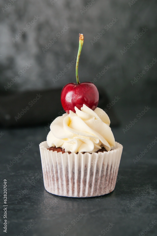 Tasty cherry cupcake on black background