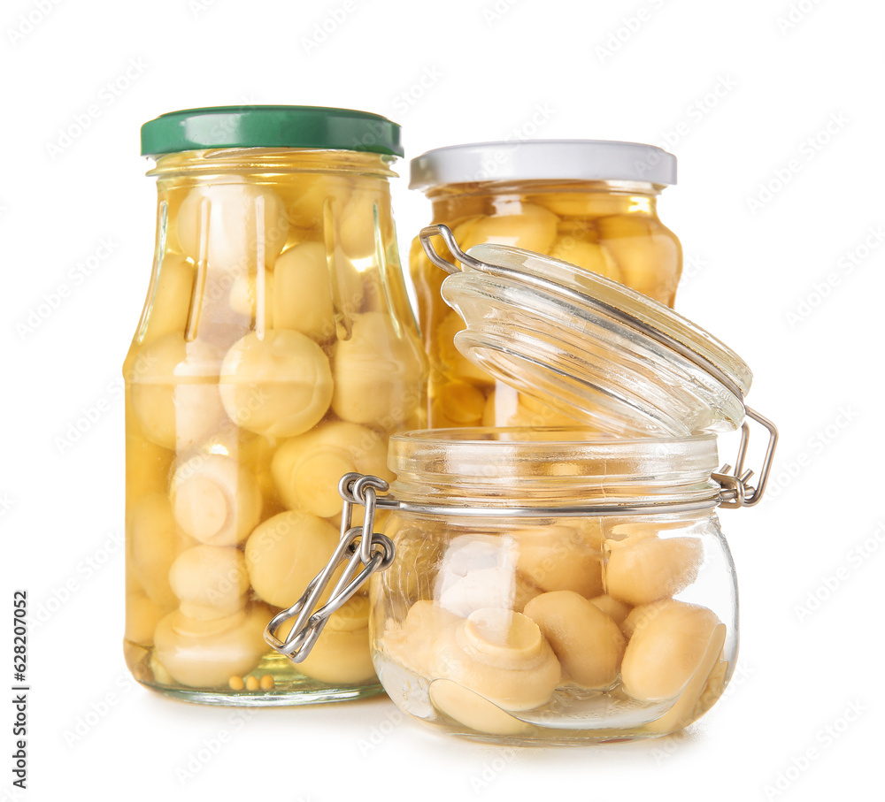 Jars with canned mushrooms on white background