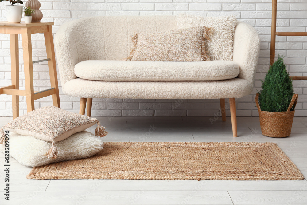 Interior of light living room with white sofa and wicker carpet