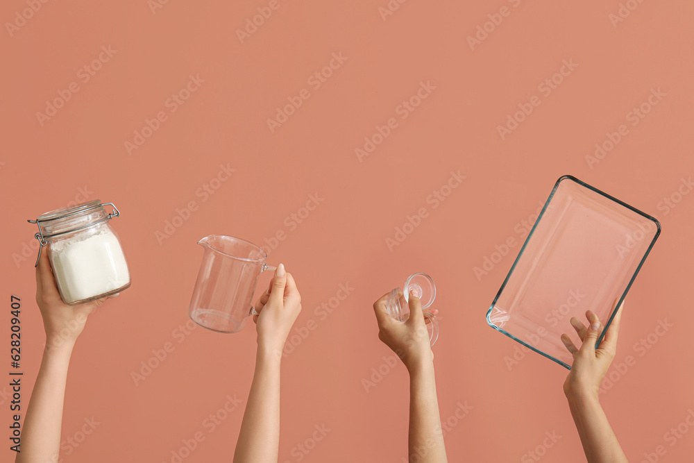 Female hands with baking utensils on pink background