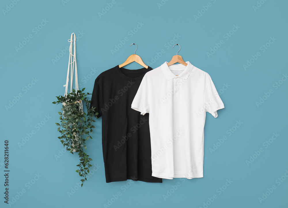 Stylish t-shirts hanging on blue background