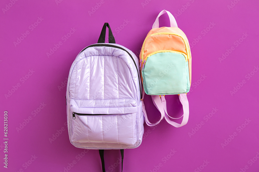 Color school backpacks on purple background