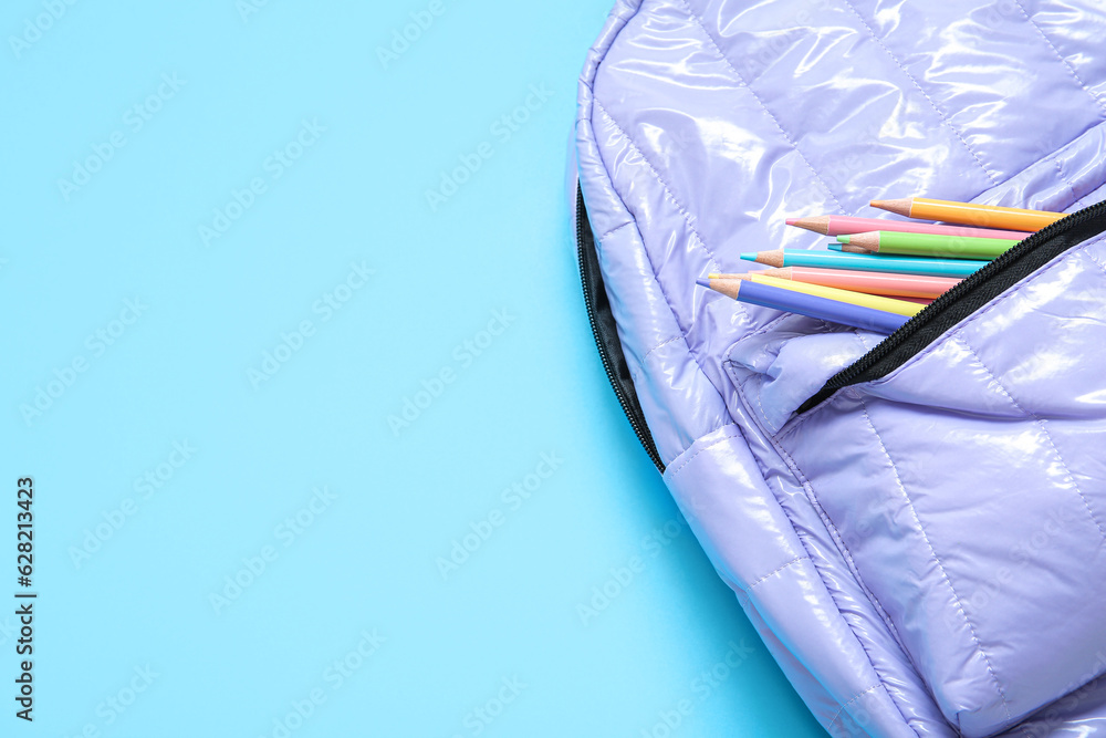 Lilac school backpack with stationery on blue background