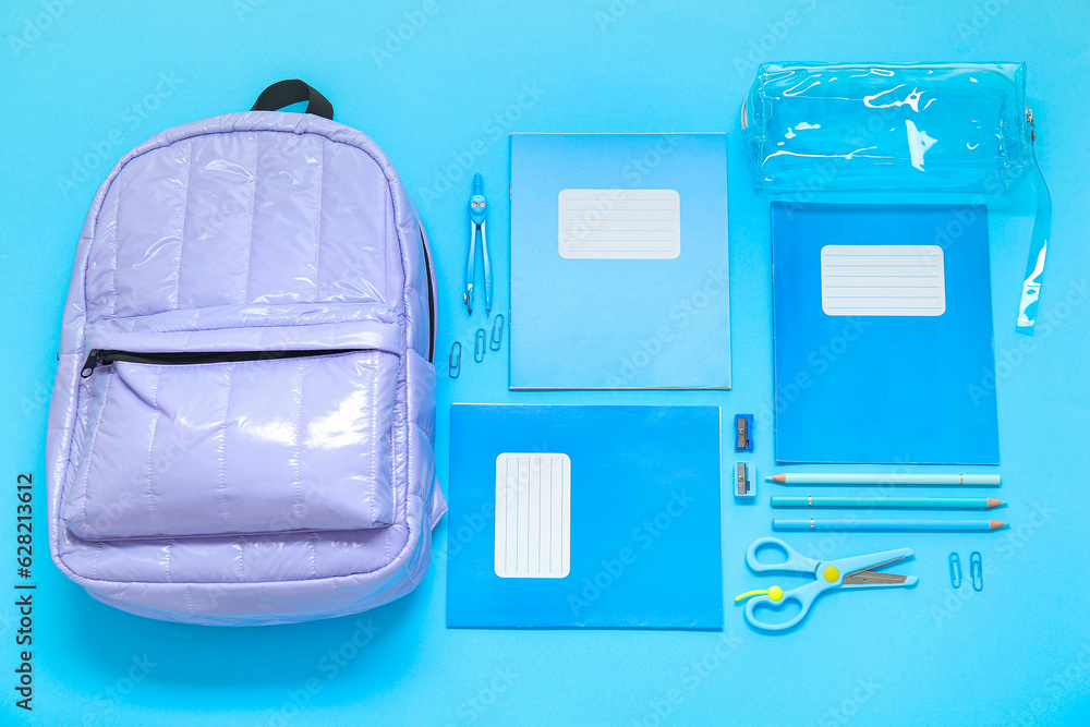 Lilac school backpack with stationery on blue background