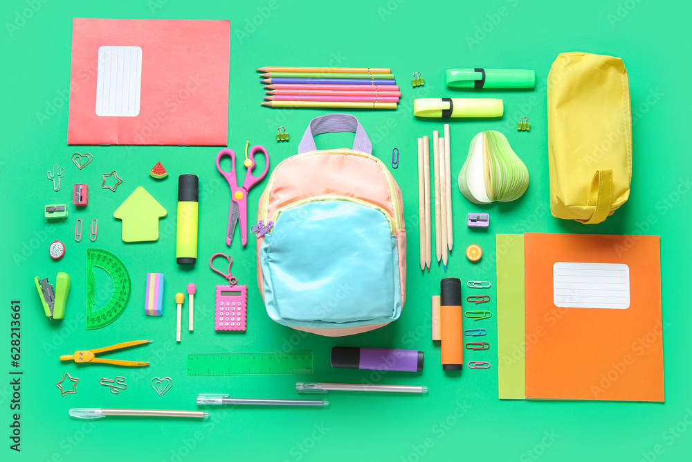 Color school backpack with different stationery on green background