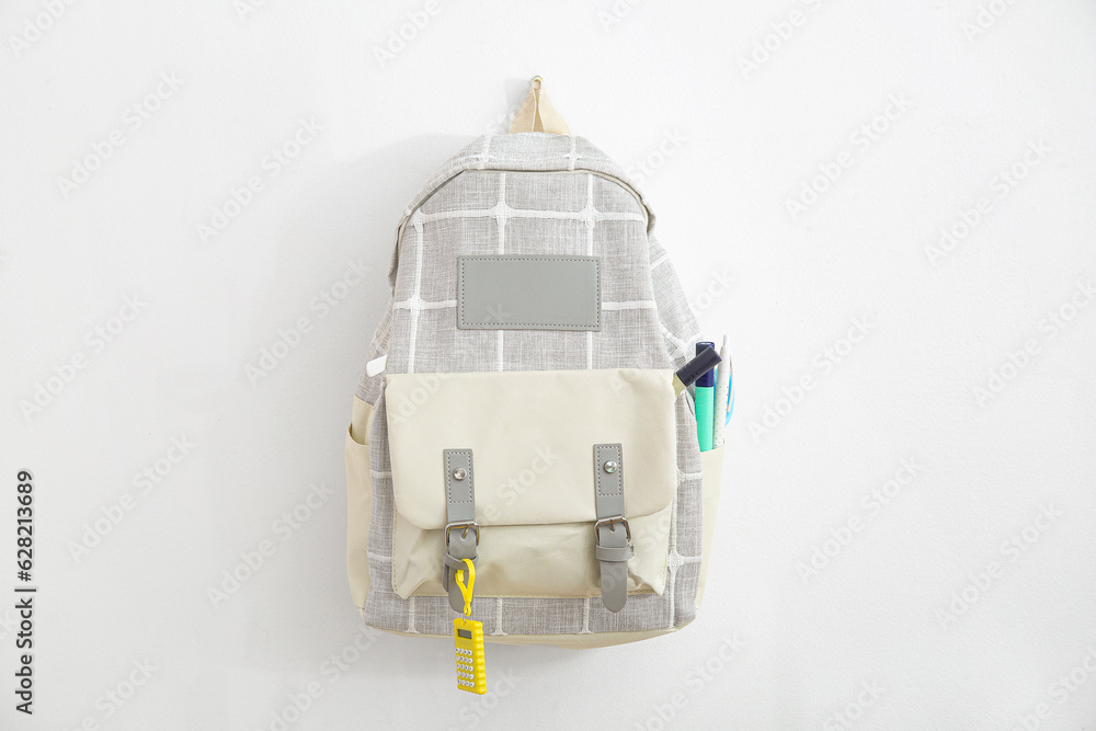 Grey school backpack with stationery on white background