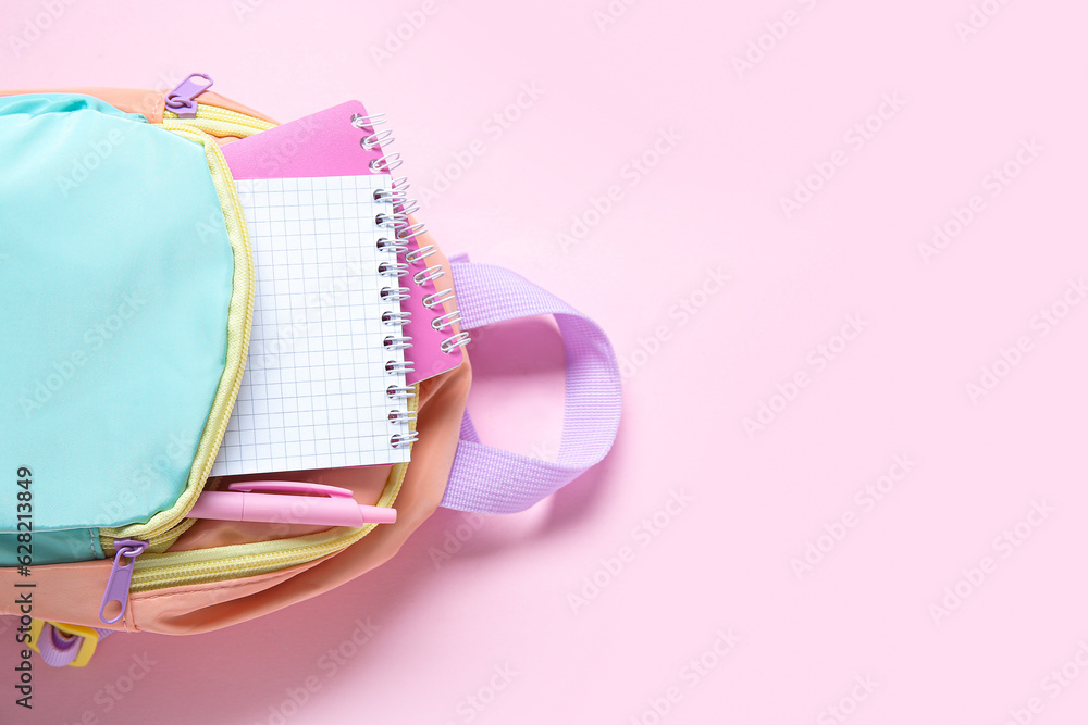 Color school backpack with stationery on pink background