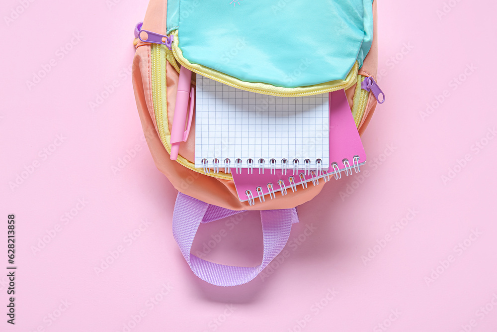 Color school backpack with stationery on pink background