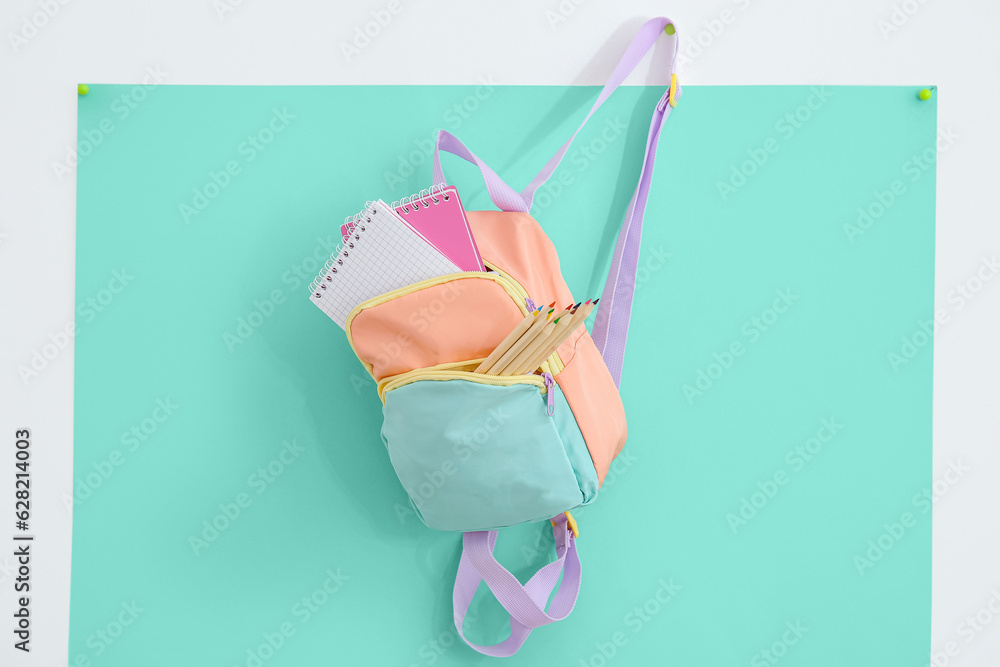 Color school backpack with stationery on turquoise background