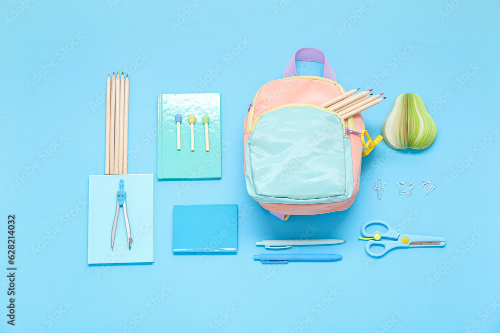 Color school backpack with different stationery on blue background