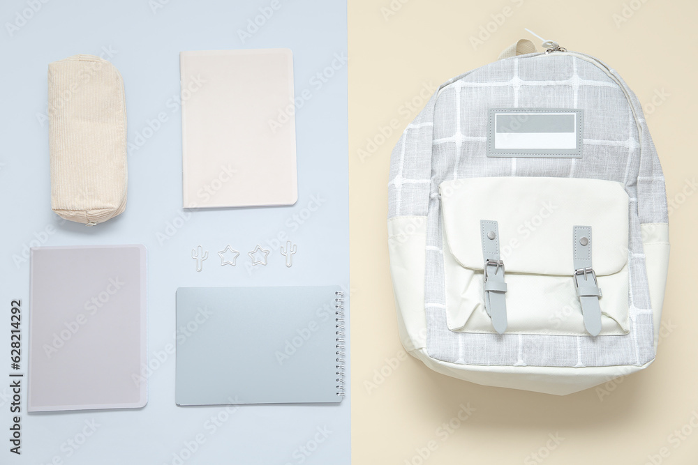 Grey school backpack with stationery on color background