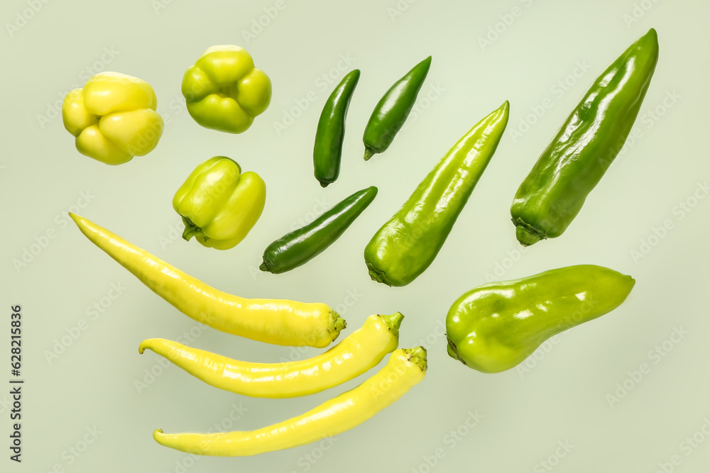 Different fresh peppers on green background