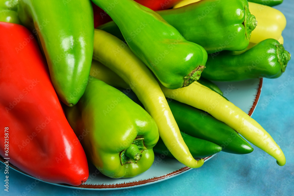 Plate with different fresh peppers on blue background