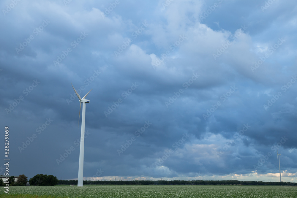 two wind turbine stand in the farmland with cloudy sky in the background