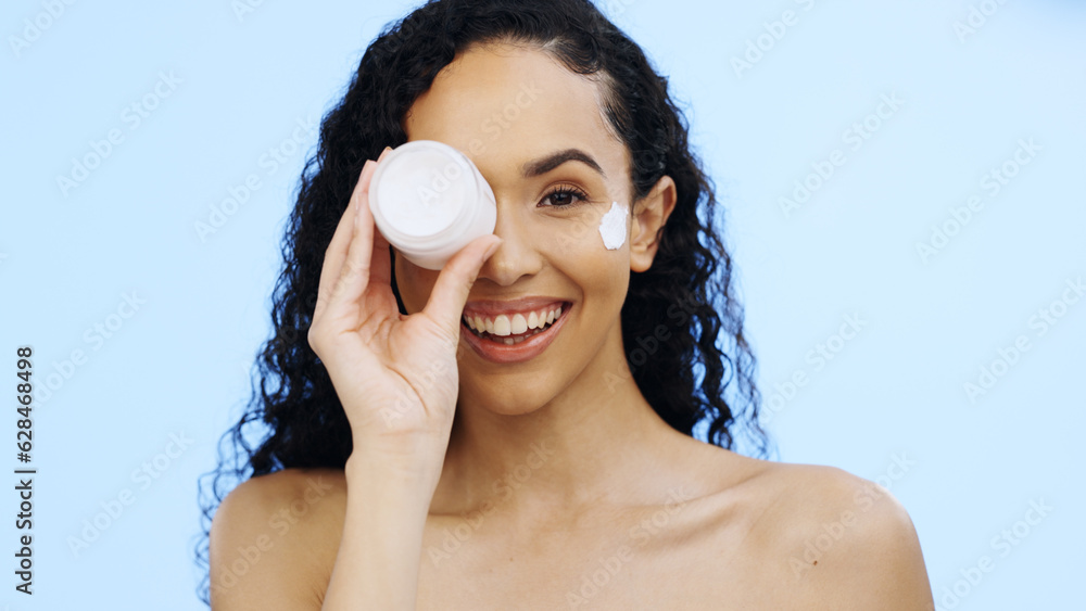 Face, cream jar and beauty of woman, cosmetics and smile on blue background. Facial lotion, skincare