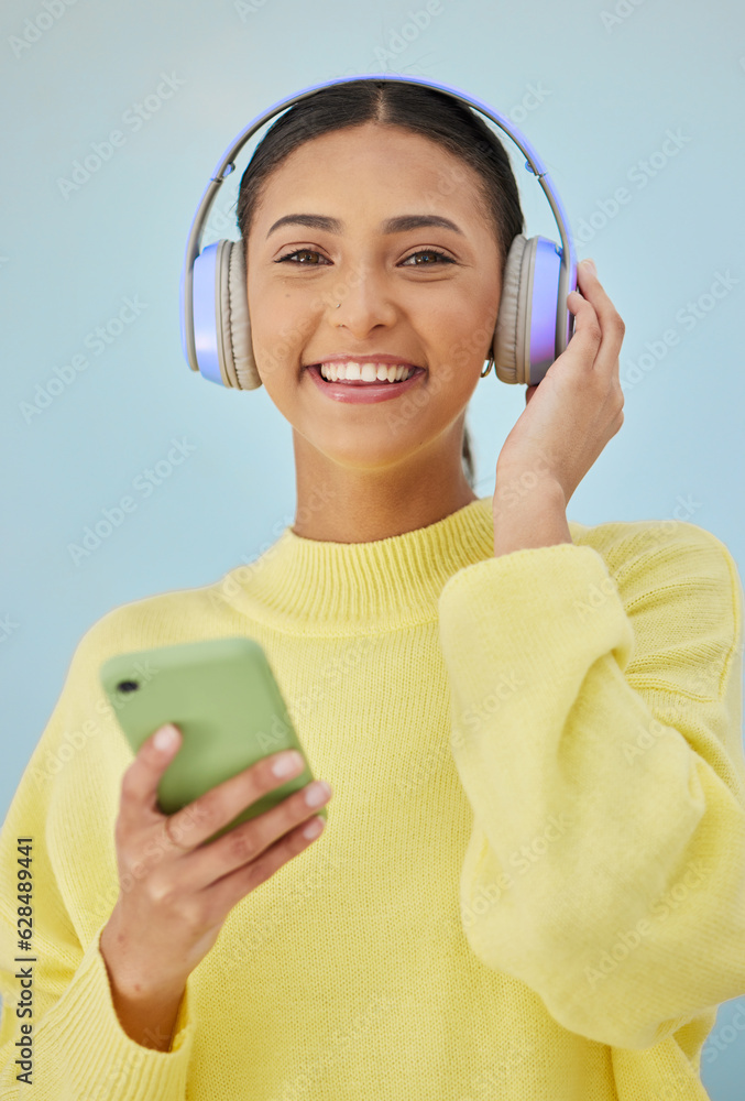 Portrait of woman with phone, headphones and smile in studio for social media, mobile app and stream