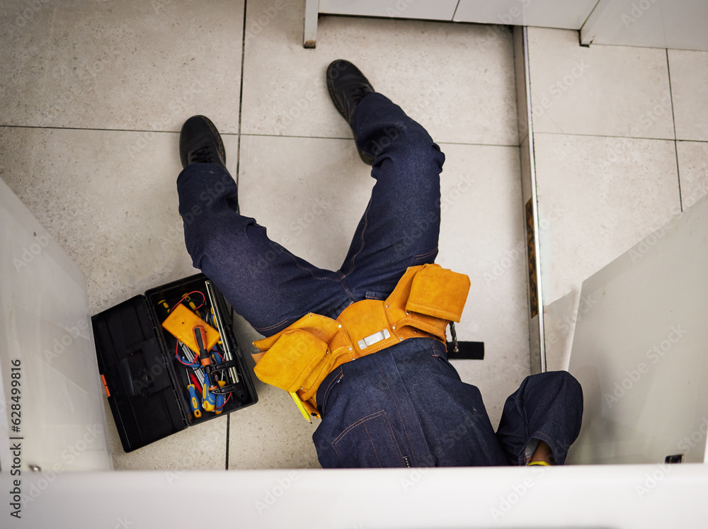 Kitchen, maintenance and repair with a plumber on the floor of a home to fix a leak, issue or proble