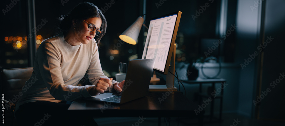 Nighttime productivity: Young businesswoman typing on laptop in home office