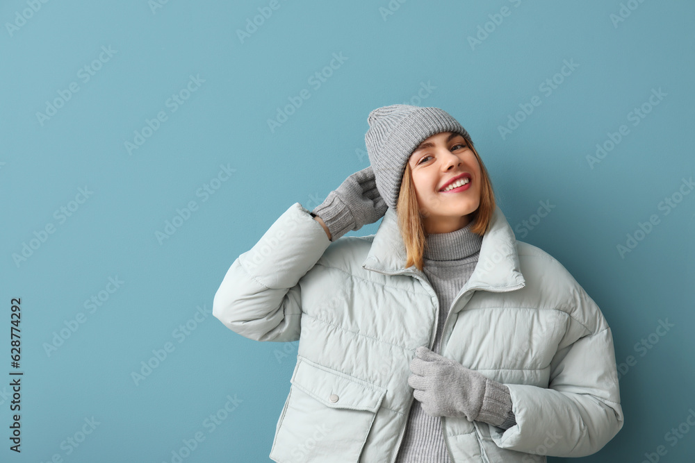 Frozen young woman in winter clothes on blue background