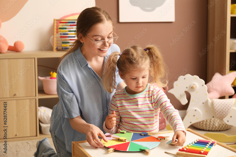 Mother and her little daughter playing matching game with clothespins at home